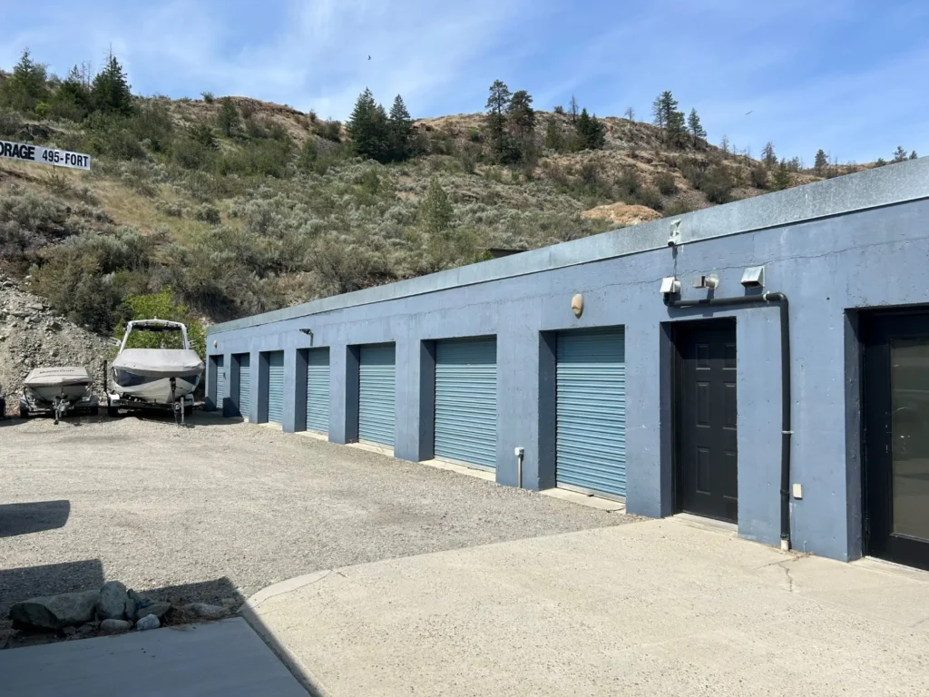 Row of blue storage units against a hillside under a clear sky.